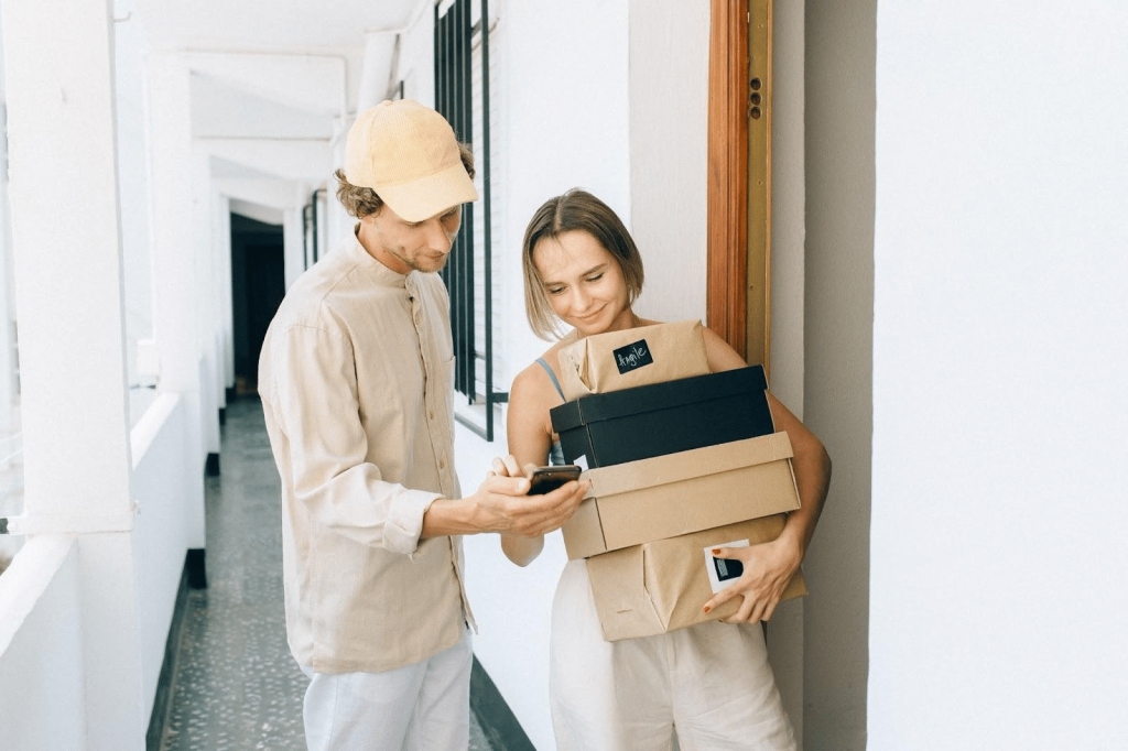 Pessoa recebendo compras em casa, fazendo a confirmação pelo smartphone.